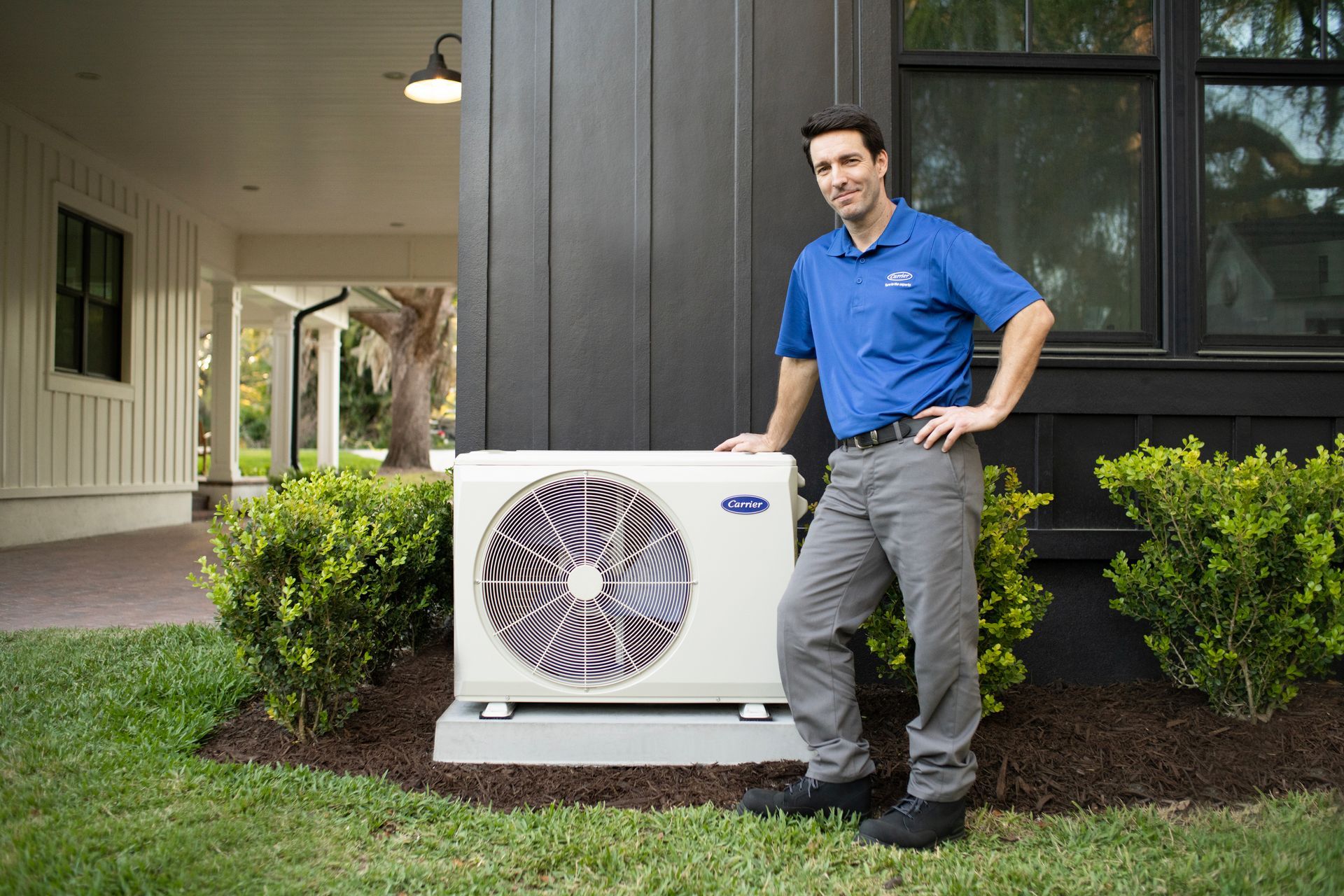 An Agility Heating & Air technician beside a new Carrier system at a Central Texas home